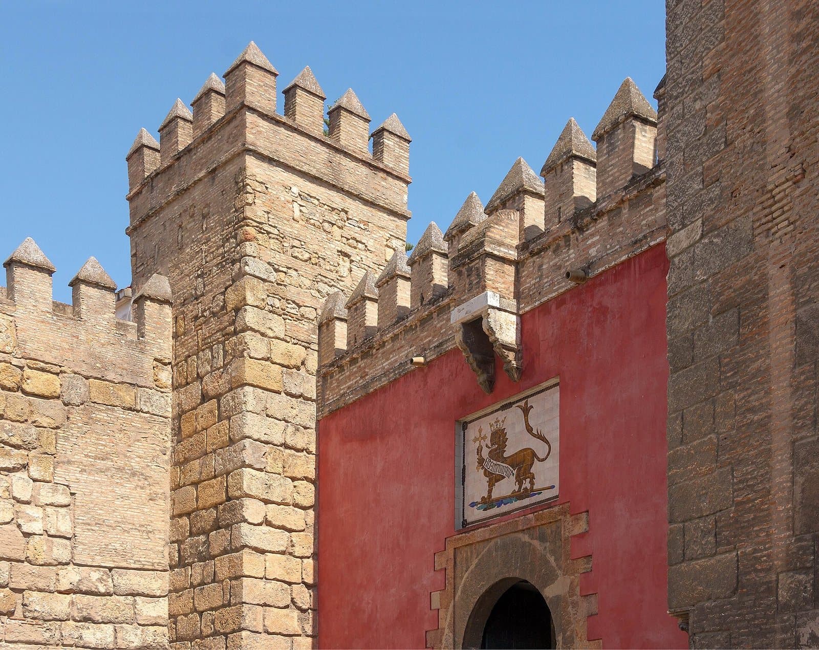 Royal Alcázar of Seville: the Lion Gate in its red wall between the battlemented towers