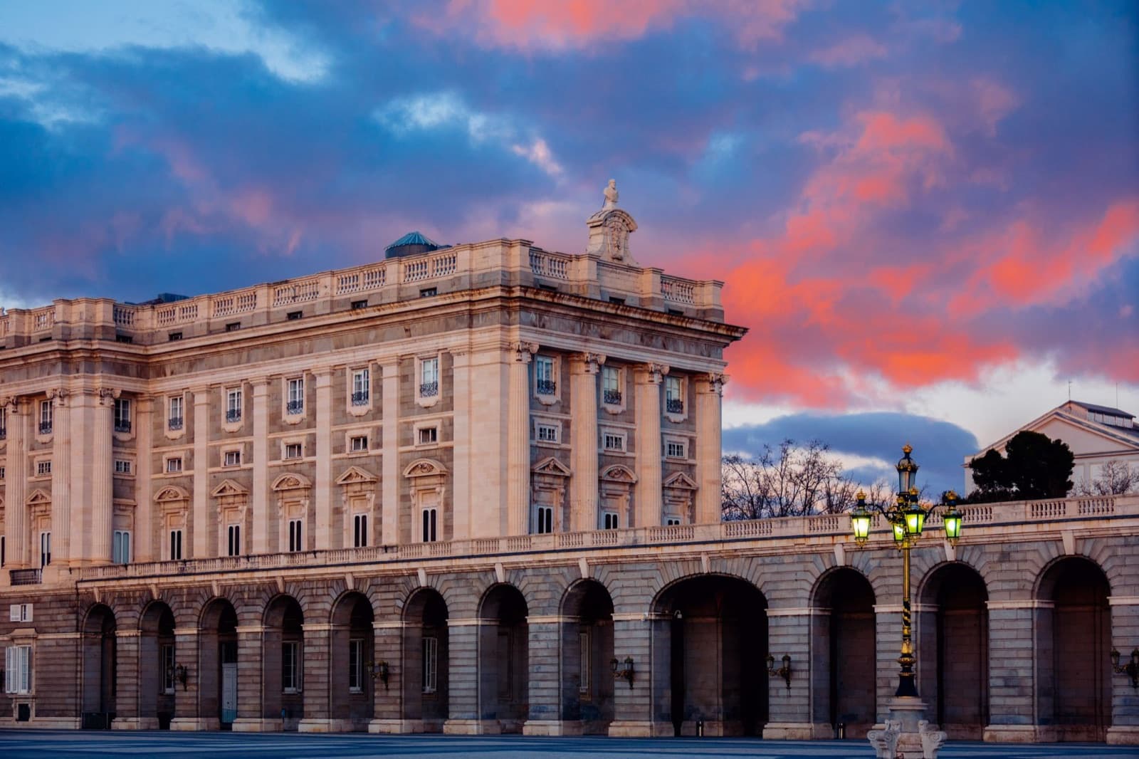 Royal Palace of Madrid: the palace and an arcade under a sunset sky