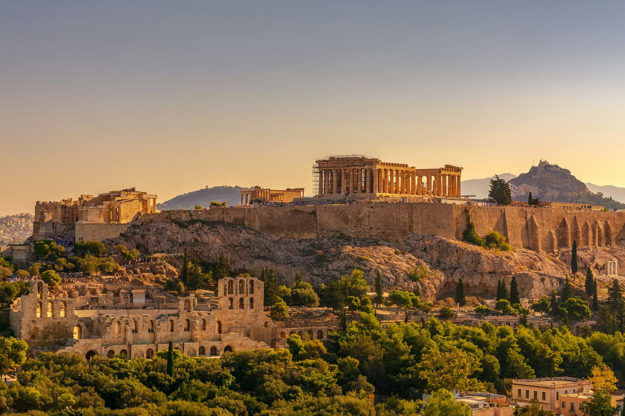 Acropolis Museum: the Acropolis at golden hour from Filopappou Hill, with the Odeon of Herodes Atticus on the south slope below